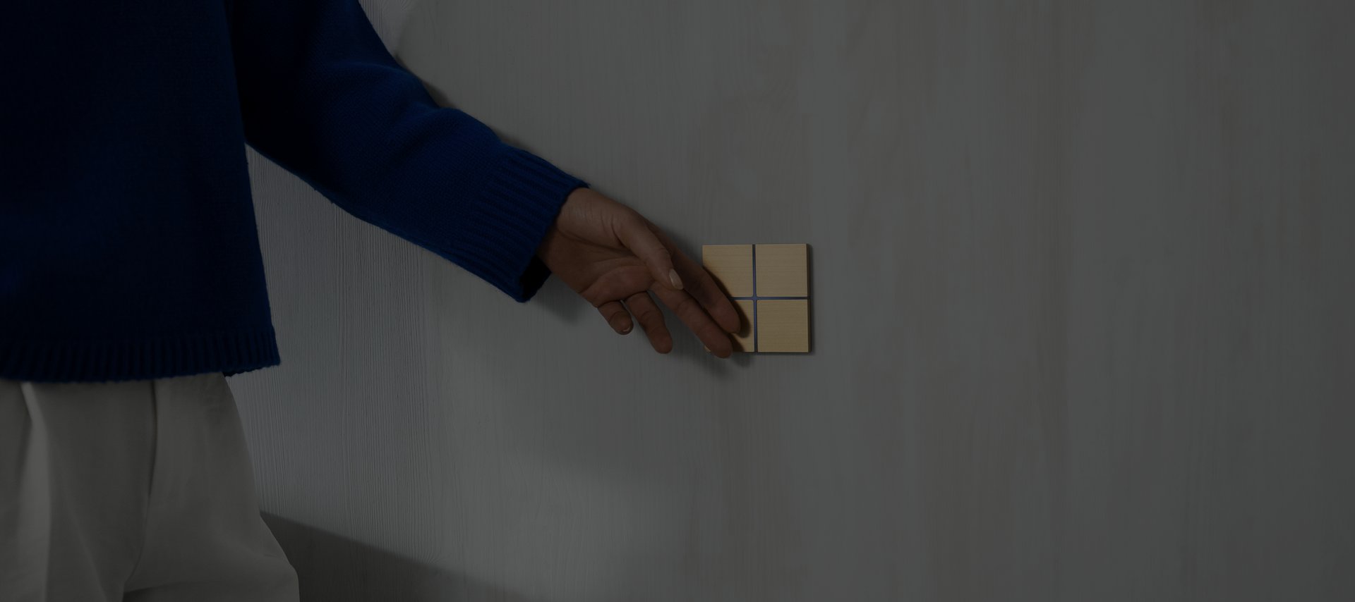 A hand operating a brass Basalte Sentido KNX keypad